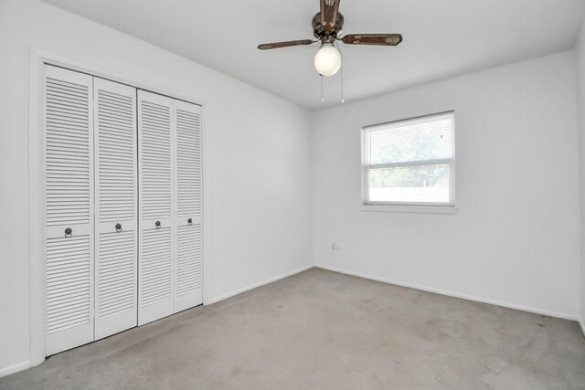 unfurnished bedroom with ceiling fan, a closet, and light colored carpet