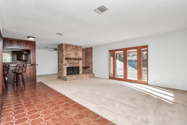 unfurnished living room featuring carpet, ceiling fan, and a brick fireplace