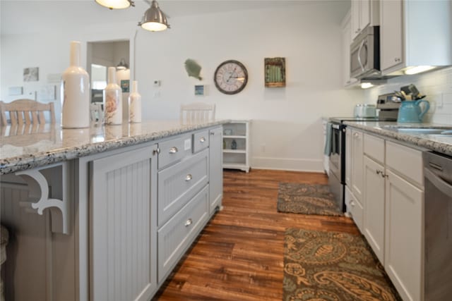 kitchen featuring light stone counters, white cabinets, decorative light fixtures, dark wood-type flooring, and appliances with stainless steel finishes