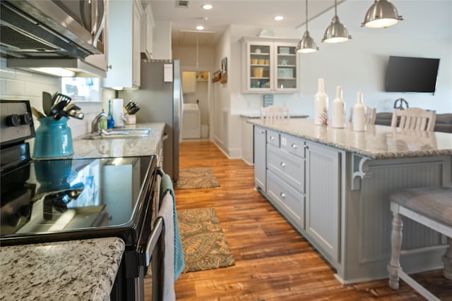 kitchen featuring a kitchen breakfast bar, hanging light fixtures, white cabinets, stainless steel appliances, and hardwood / wood-style floors