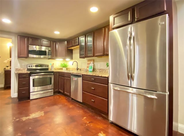 kitchen with light stone countertops, sink, and stainless steel appliances