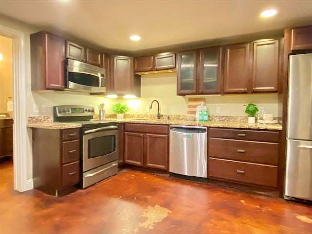 kitchen with light stone counters, stainless steel appliances, and sink