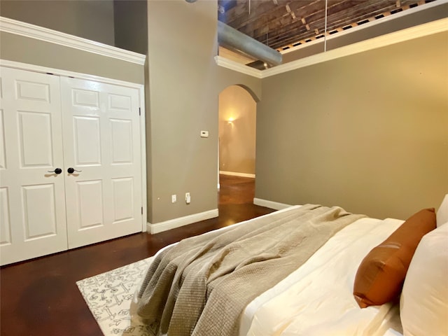 bedroom with a high ceiling, ornamental molding, dark hardwood / wood-style floors, and a closet