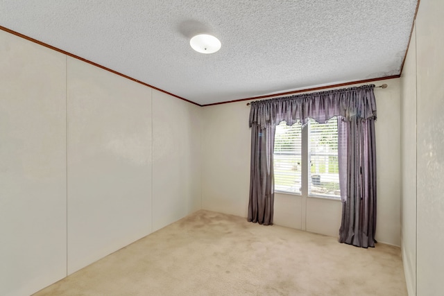 unfurnished room featuring a textured ceiling, ornamental molding, and light colored carpet