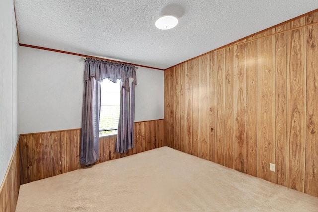 unfurnished room with carpet, wood walls, a textured ceiling, and ornamental molding