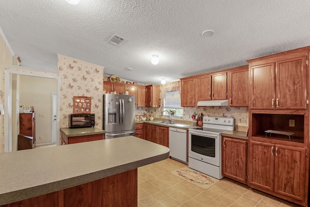 kitchen with a textured ceiling, sink, and white appliances