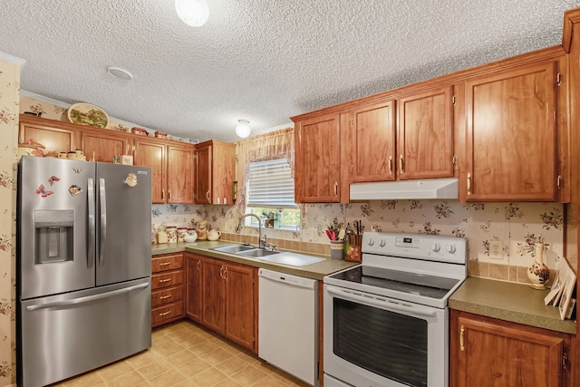 kitchen with ornamental molding, white appliances, a textured ceiling, and sink