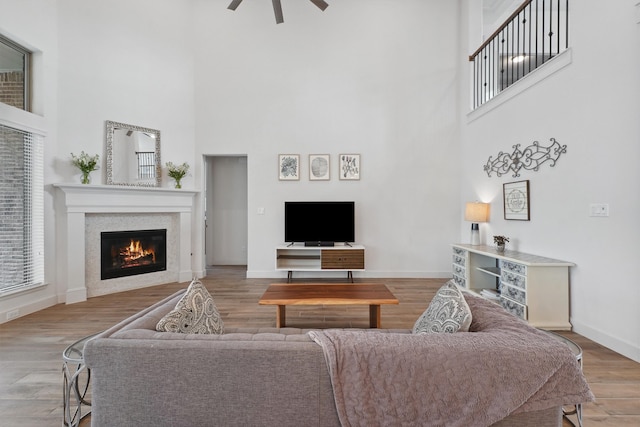 living room featuring ceiling fan, a high ceiling, and wood-type flooring