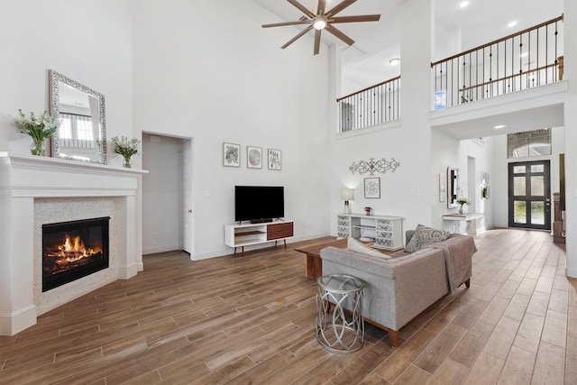 living room featuring wood-type flooring, a towering ceiling, and ceiling fan