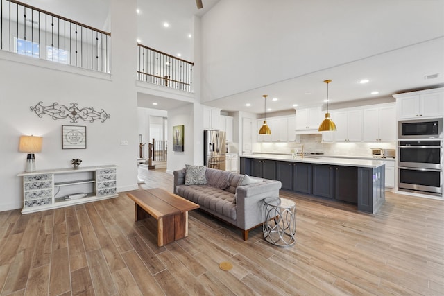 living room with light hardwood / wood-style flooring and a towering ceiling