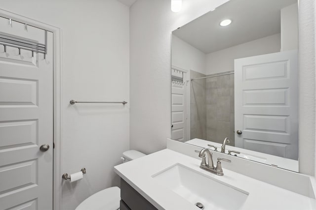 bathroom with a tile shower, vanity, and toilet