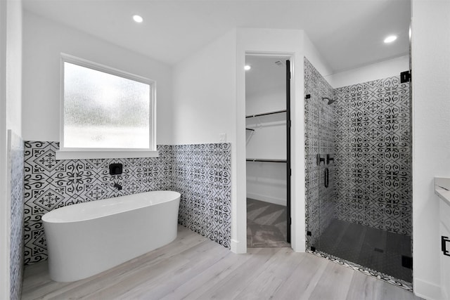 bathroom featuring shower with separate bathtub, tile walls, and hardwood / wood-style floors