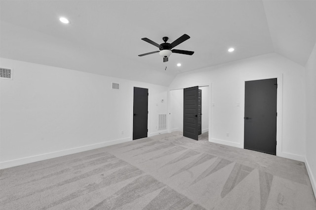 unfurnished bedroom with ceiling fan, a closet, light carpet, and vaulted ceiling