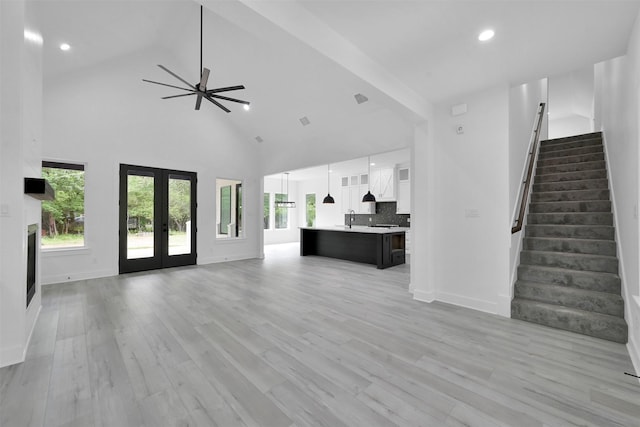 unfurnished living room with french doors, light hardwood / wood-style floors, high vaulted ceiling, and ceiling fan