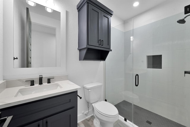 bathroom featuring wood-type flooring, vanity, toilet, and walk in shower