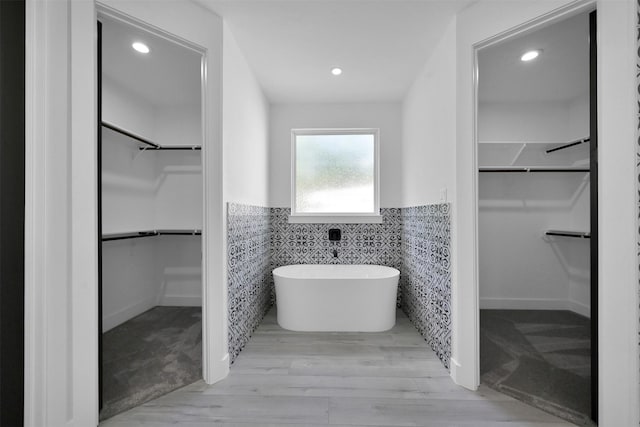 bathroom with hardwood / wood-style flooring, a bathtub, and tile walls