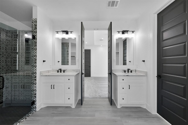 bathroom with hardwood / wood-style flooring, vanity, and tiled shower