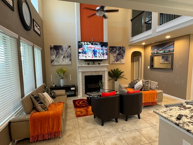 living room with ceiling fan, a towering ceiling, and light tile patterned floors