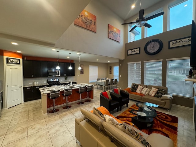 living room with ceiling fan, light tile patterned floors, and high vaulted ceiling