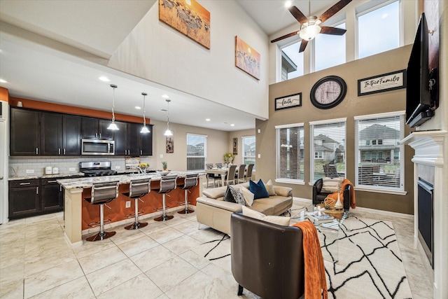 living room with ceiling fan, light tile patterned floors, and a towering ceiling