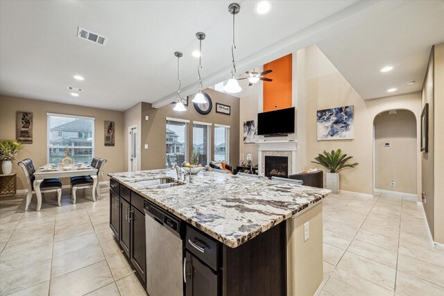 kitchen featuring an island with sink, sink, stainless steel dishwasher, and decorative light fixtures