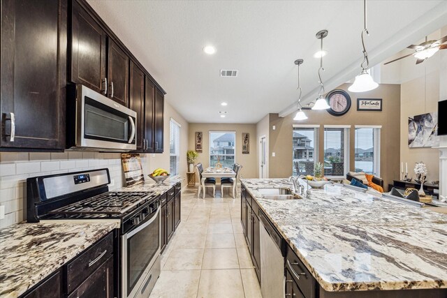 kitchen featuring stainless steel appliances, light stone countertops, and backsplash