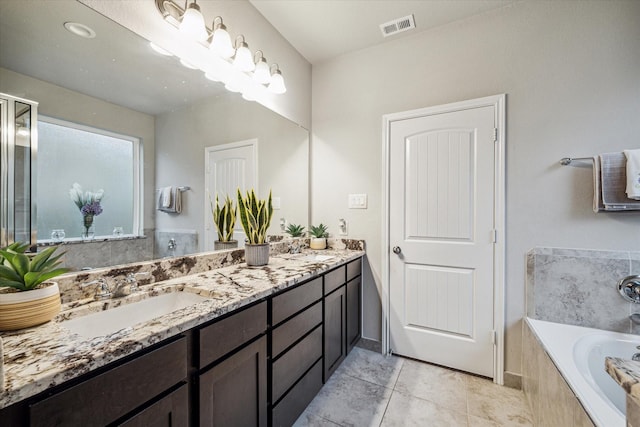 bathroom featuring tile patterned flooring, vanity, and a relaxing tiled tub