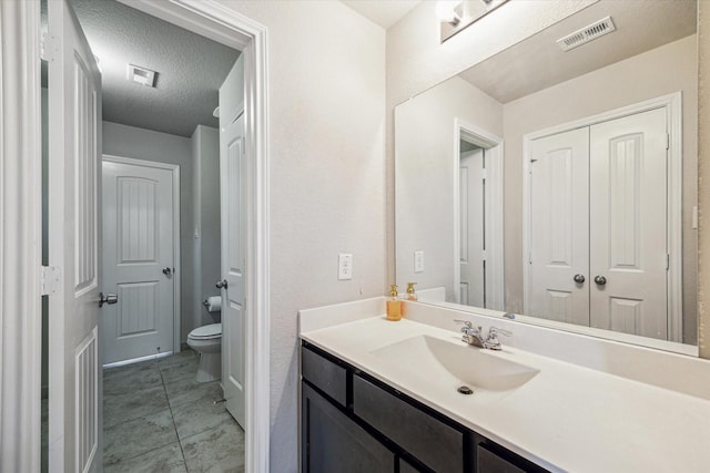 bathroom featuring vanity, toilet, and a textured ceiling