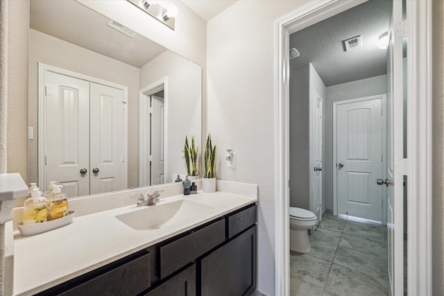 bathroom with vanity, a textured ceiling, and toilet