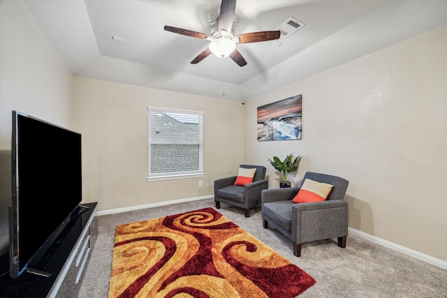 sitting room with ceiling fan, light colored carpet, and a tray ceiling