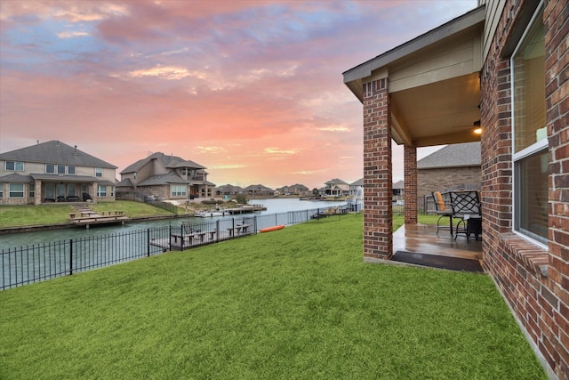 yard at dusk featuring a water view