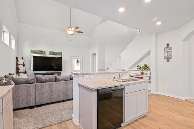 kitchen featuring dishwasher, sink, white cabinetry, light hardwood / wood-style flooring, and a center island with sink