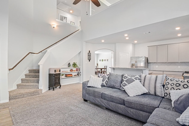 living room featuring a high ceiling, light hardwood / wood-style floors, and ceiling fan