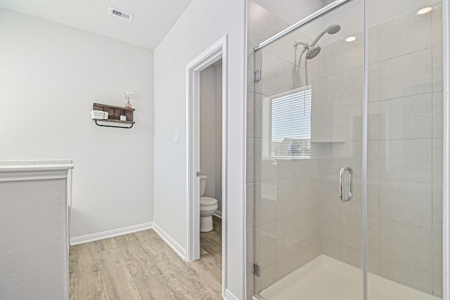 bathroom featuring hardwood / wood-style floors, toilet, and an enclosed shower