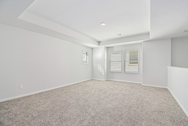 carpeted spare room with a tray ceiling