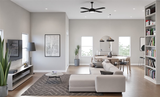 living room with hardwood / wood-style floors, ceiling fan, and a high ceiling