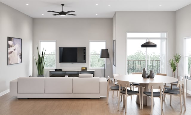 living room with light wood-type flooring, a towering ceiling, and ceiling fan