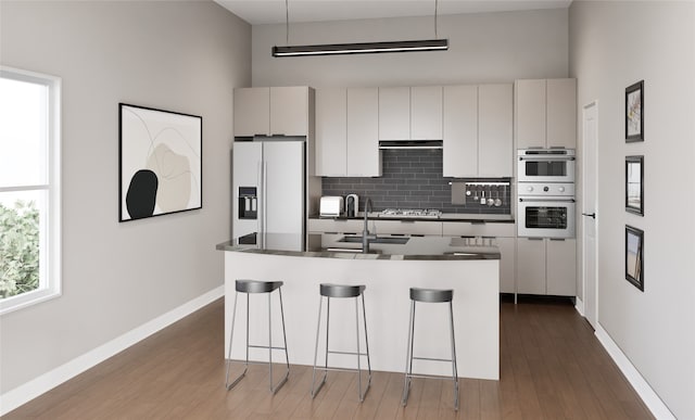 kitchen with white appliances, a kitchen island with sink, white cabinets, tasteful backsplash, and dark hardwood / wood-style flooring