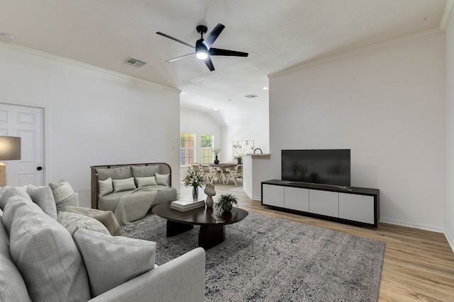 living room with a textured ceiling, lofted ceiling, ceiling fan, light hardwood / wood-style flooring, and ornamental molding