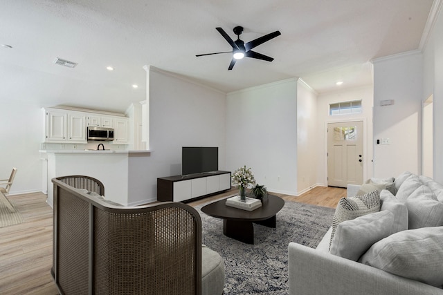 living room with light wood-type flooring, ornamental molding, and ceiling fan