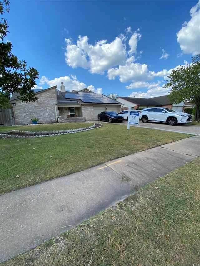 view of front of property featuring solar panels, a front lawn, and a garage