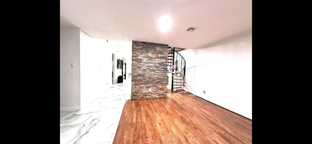 unfurnished living room featuring wood finished floors, visible vents, and stairs