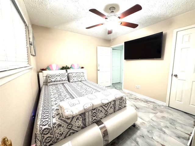 bedroom featuring marble finish floor, a ceiling fan, baseboards, and a textured ceiling