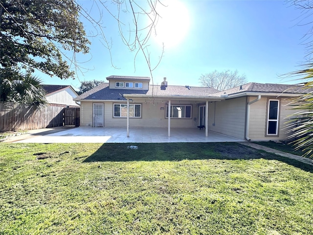 rear view of house with a yard, a patio area, fence, and a shingled roof