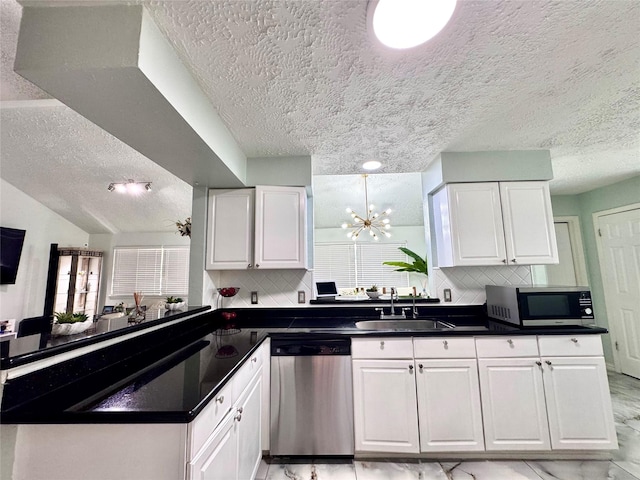 kitchen featuring a peninsula, a sink, white cabinetry, appliances with stainless steel finishes, and dark countertops