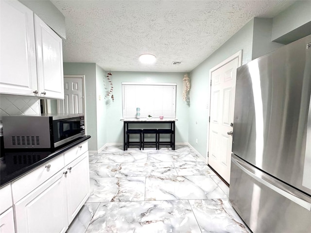 kitchen featuring marble finish floor, appliances with stainless steel finishes, white cabinetry, and baseboards