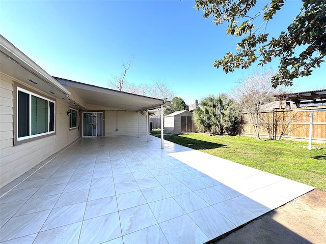 view of patio featuring an outbuilding, a fenced backyard, driveway, and a storage unit