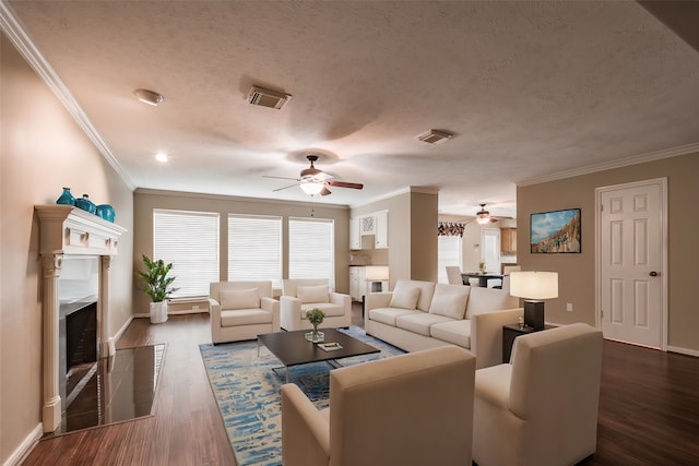 living room with a textured ceiling, ceiling fan, dark wood-type flooring, and crown molding