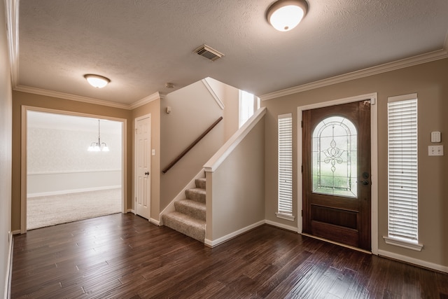 foyer entrance with ornamental molding, a textured ceiling, a chandelier, and dark wood-type flooring