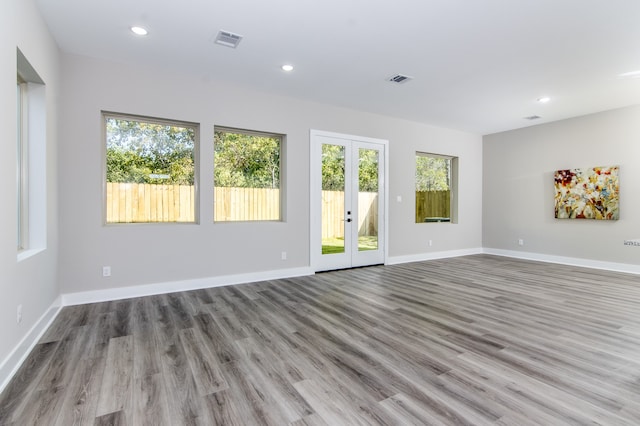 spare room featuring french doors, a wealth of natural light, and light wood-type flooring